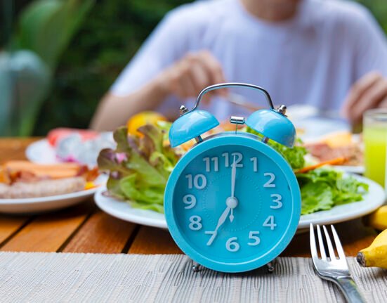 A clock and a healthy meal representing the intermittent fasting for fat loss schedule.